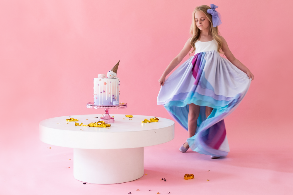A child dancing around a birthday cake wearing the unicorn chiffon dress