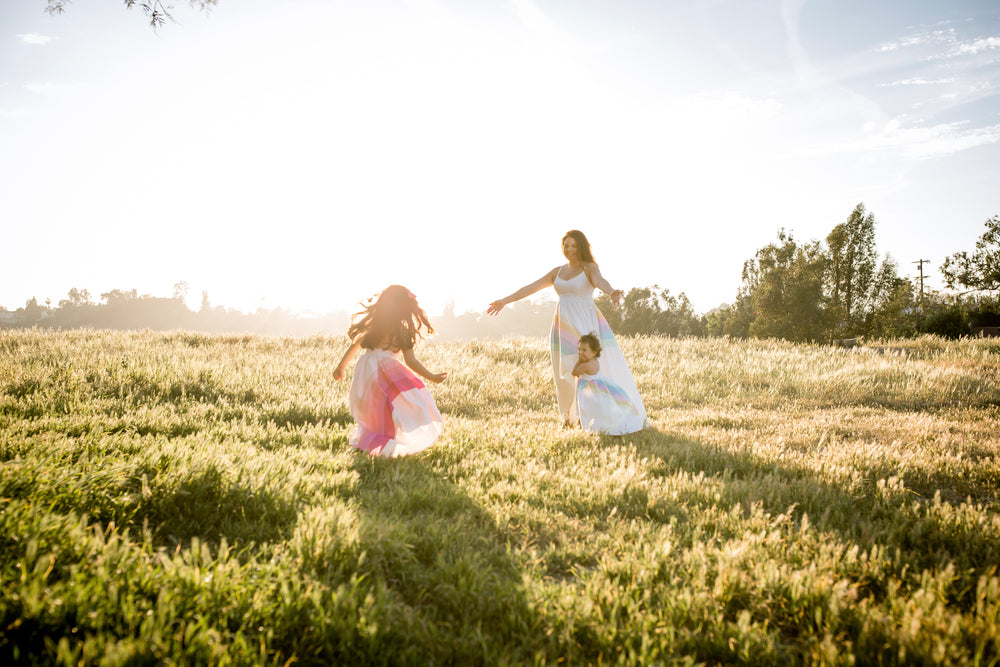 mom and children dancing in a field wearing the classic rainbow dresses
