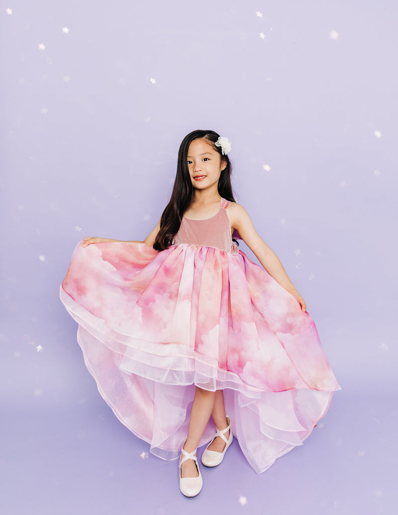 Girl wearing a white flower in her hair and a pink cloud designed high low dress