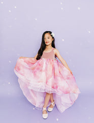 Girl wearing a white flower in her hair and a pink cloud designed high low dress