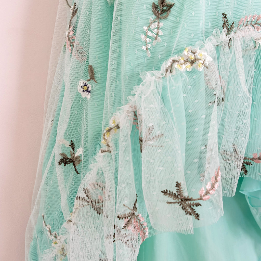 Close up of a Pleiades Designs embroidered floral and teal chiffon ruffle hem