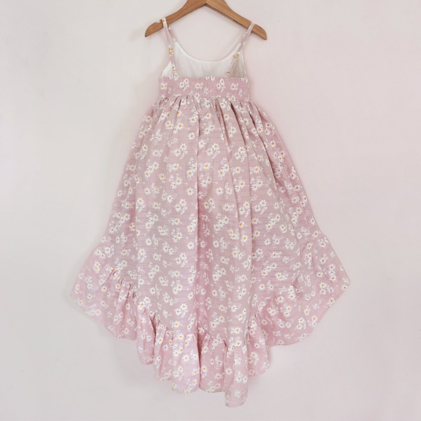 
                  
                    Back of a Pleiades Designs pink high low dress with a ruffle hem and a daisy pattern
                  
                