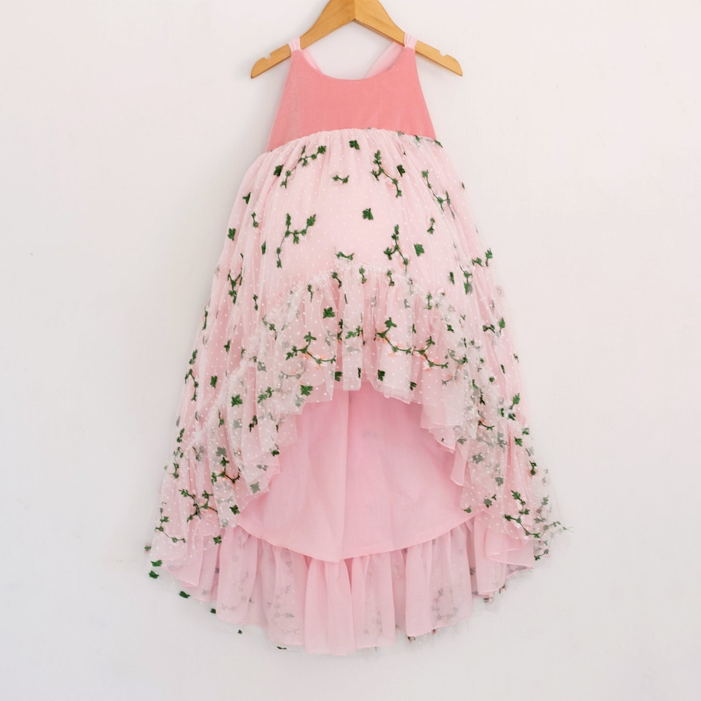 Front of a Pleiades Designs pink high low dress with a pink velvet bodice, embroidered rosebud design, and a rufffle hem