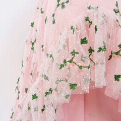 Close up of a Pleiades Designs ruffle hem with two layers. The top layer is an embroidered rosebud design