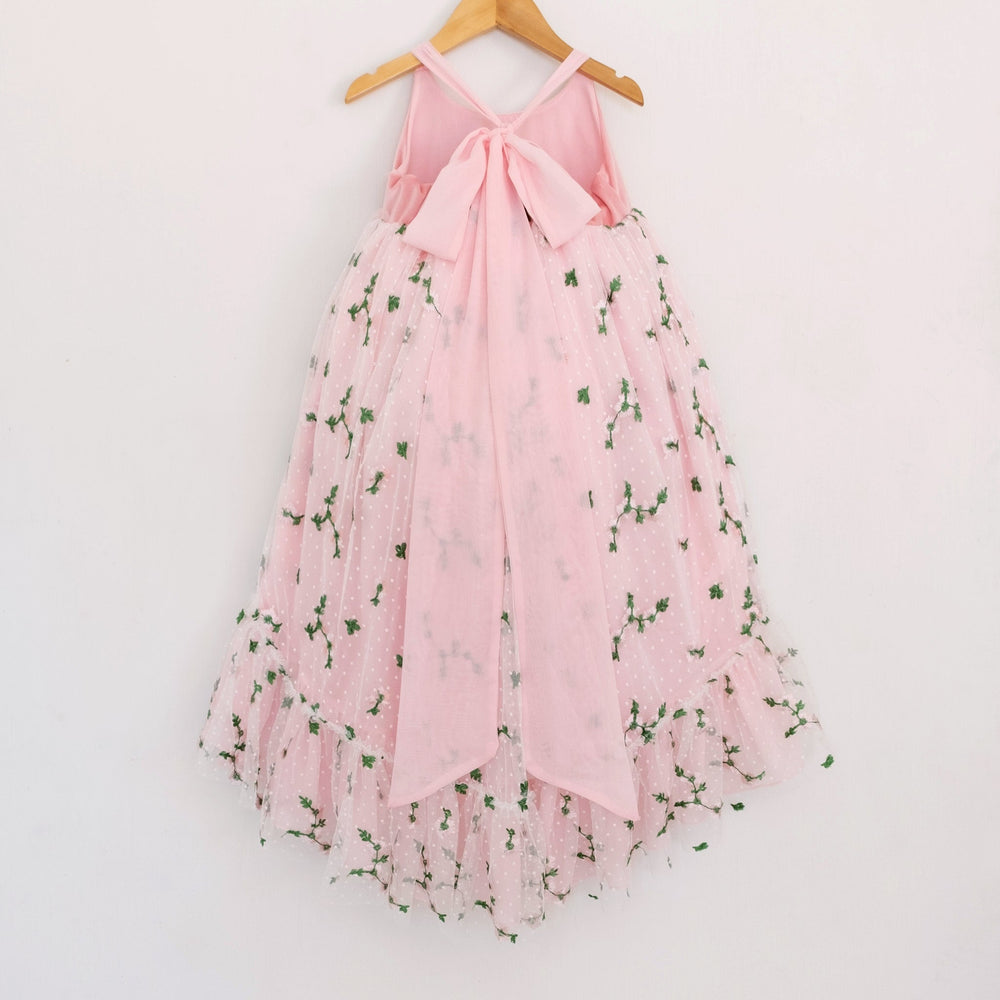 Back of a Pleiades Designs pink high low dress with a pink chiffon bow back, embroidered rosebud design, and a rufffle hem