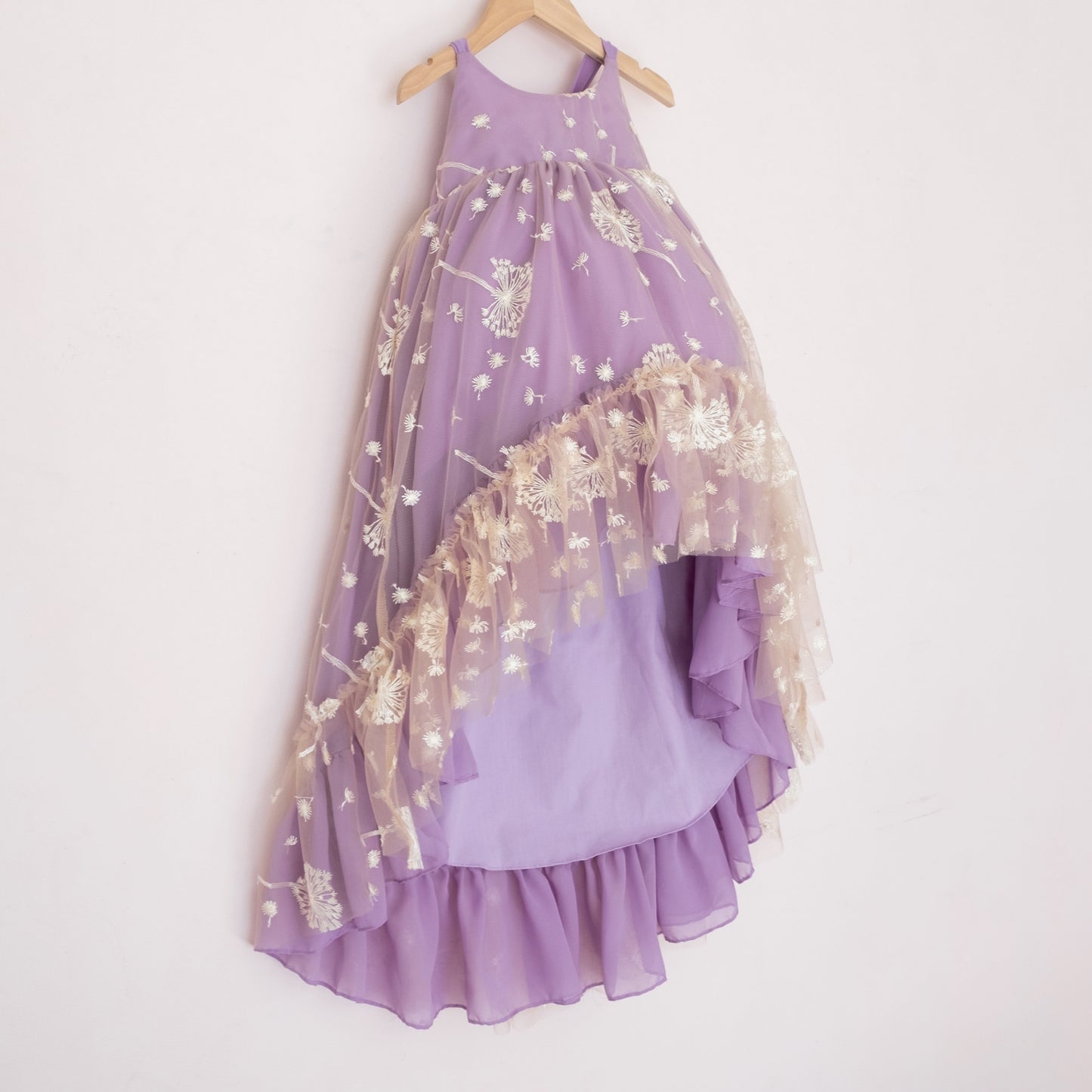 
                  
                    Side of a Pleiades Designs purple high low dress with white embroidered dandelions and a ruffle hem
                  
                