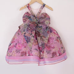 Back of a Pleiades Designs short organza dress with a purple floral pattern and a bow back