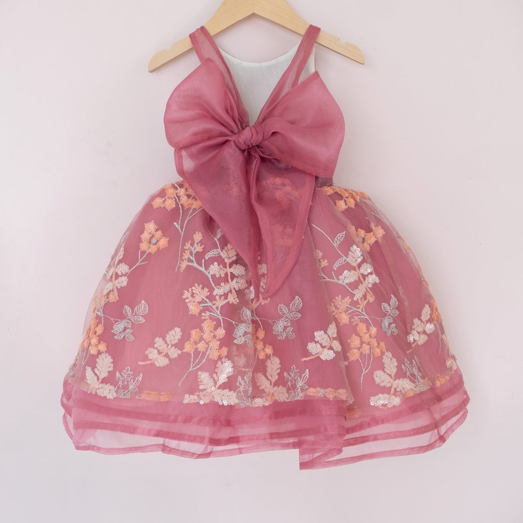 Back of a Pleiades Design short organza dress with an embroidered sequin floral and an organza bow back