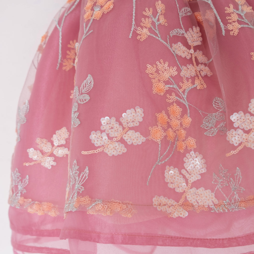 Close up of a Pleiades Designs embroidered sequin floral design over layers of mauve organza
