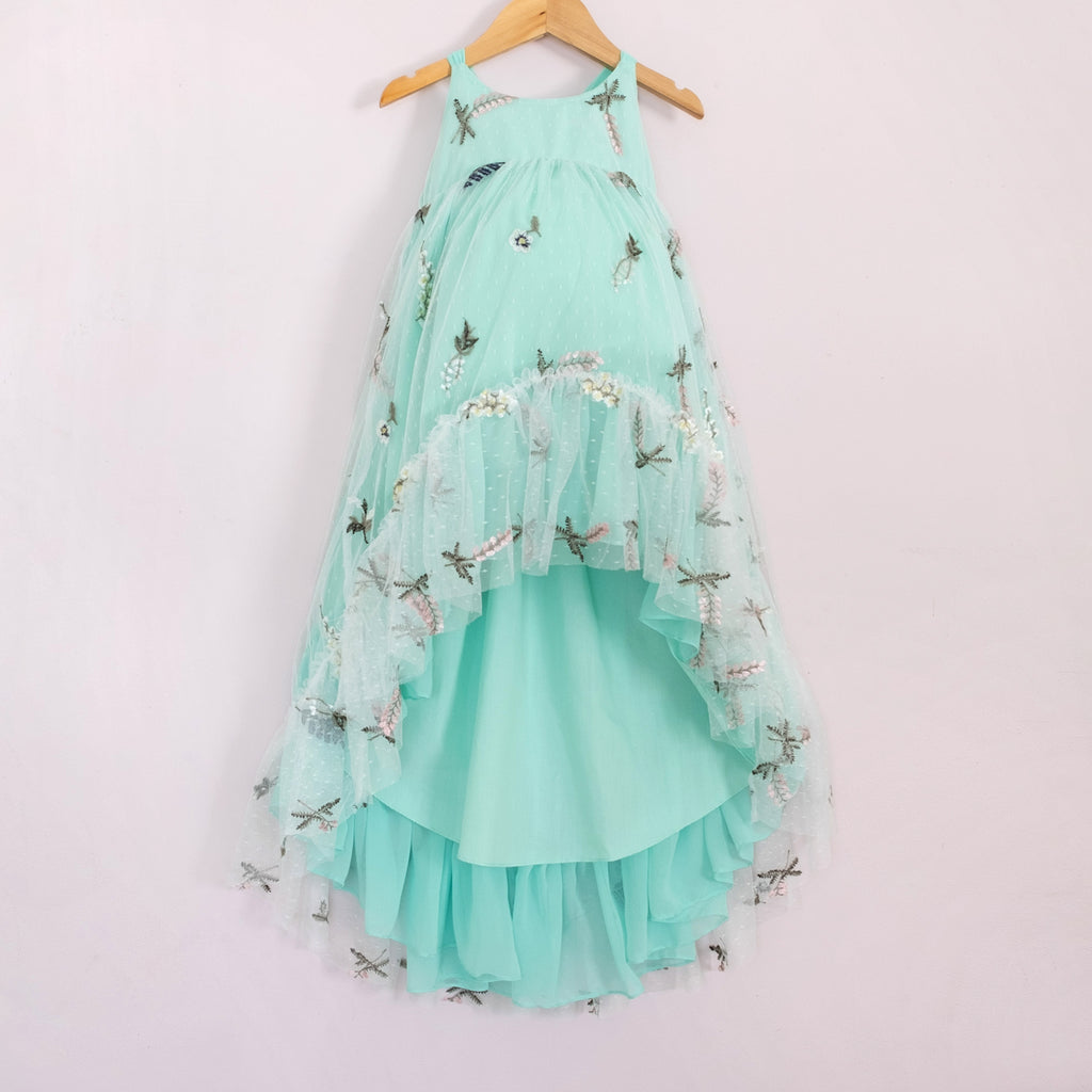 Front of a Pleiades Designs teal high low dress with embroidered florals and a ruffle hem