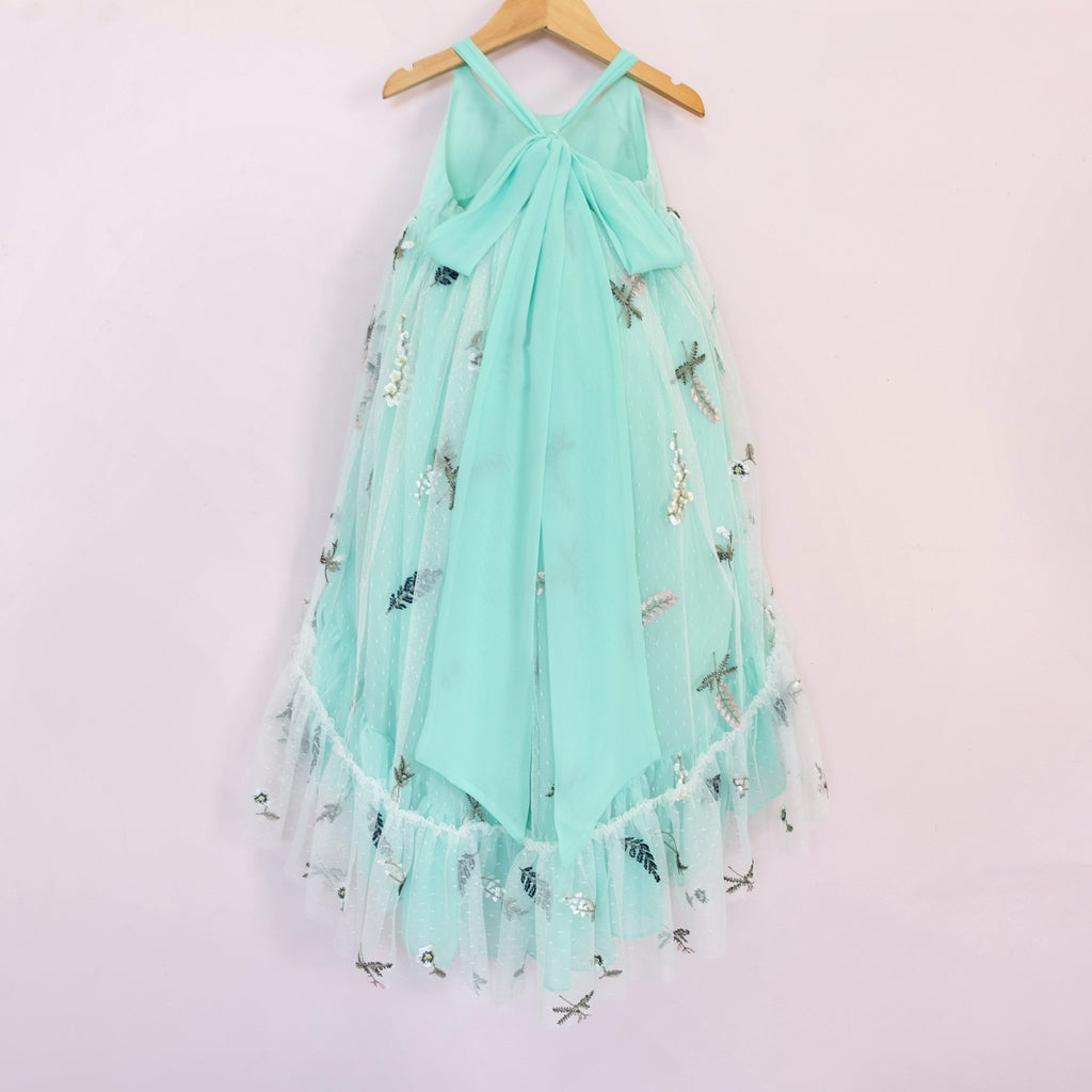 Back of a Pleiades Designs teal high low dress with embroidered florals, a ruffle hem, and a bow back