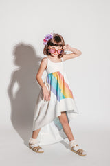 Girl wearing a white high low dress that has a bright rainbow across the front and back