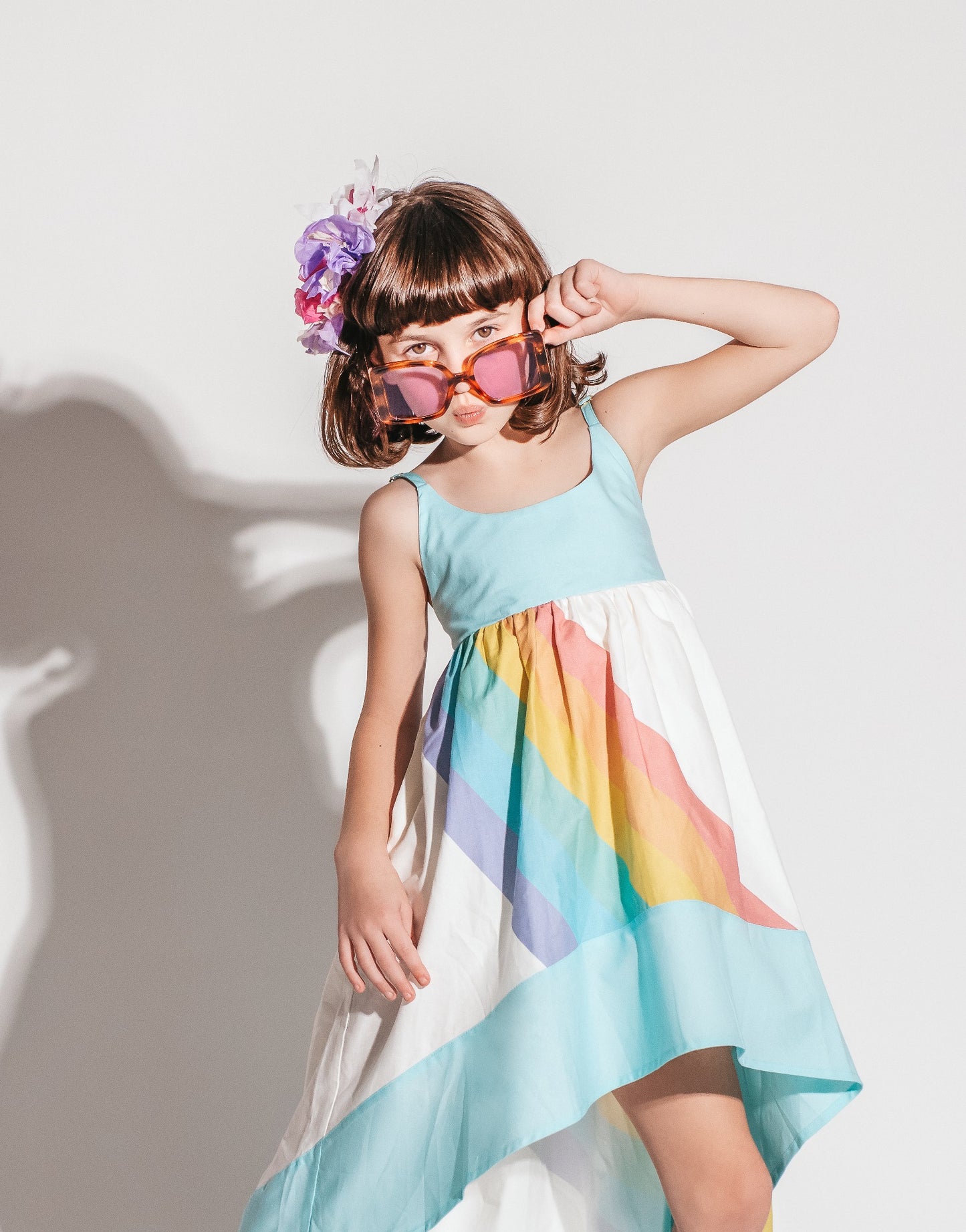 
                  
                    Girl wearing a white and aqua high low dress with a bright rainbow across the front and back
                  
                